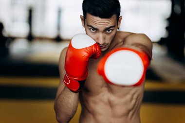 Çıplak bir gövde ve kırmızı boks eldiven ile sporcu ellerini boks spor salonunda sol el ile Hits duruyor