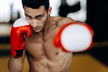 Çıplak bir gövde ve kırmızı boks eldiven ile sporcu ellerini boks spor salonunda sol el ile Hits duruyor