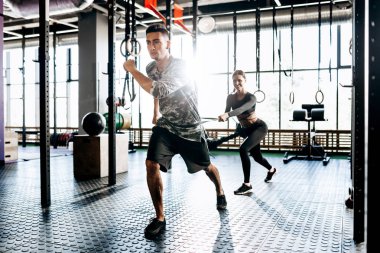 Genç atletik adam ve ince kız spor salonunda güç bandı gibi özel ekipman ile spor egzersizleri yapıyoruz