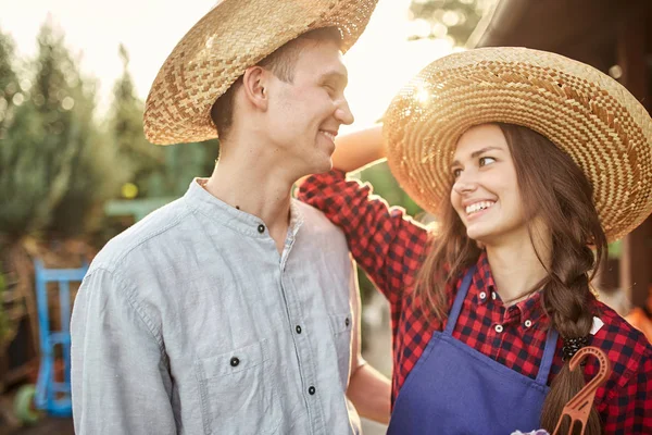 Ragazzo felice e giardinieri ragazza in un cappelli di paglia si guardano in giardino in una giornata di sole . — Foto Stock