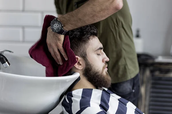Парикмахер вытирает волосы мужчинам полотенцем в парикмахерской — стоковое фото