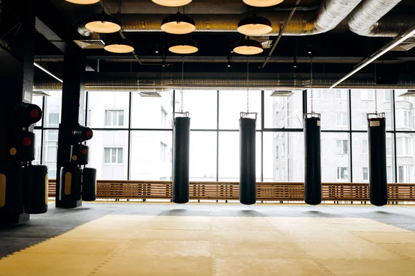 Großzügige Sporthalle mit Panoramafenstern und drei Boxsäcken — Stockfoto