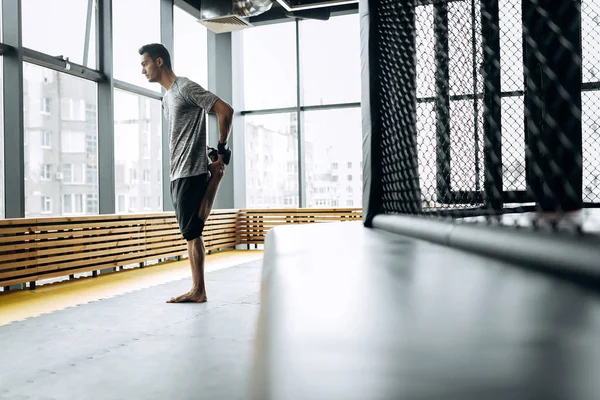 회색 t-셔츠를 입은 사람은 파노라마 창문이 있는 복싱 체육관에서 그의 팔을 뻗어 — 스톡 사진