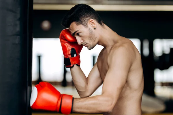 Sporcu çıplak bir gövde ve ellerinin üstünde kırmızı boks eldiven boks jimnastik salonu tetikte duruyor — Stok fotoğraf