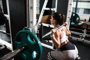 Modern spor salonunda bir halter ile spor ağız kavgası giyinmiş genç atletik kız