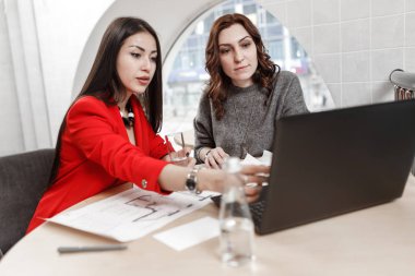 İki kız tasarımcıları dizüstü bilgisayar ve belgelerine şık ofis Projesi'nde çalışıyor. Proje oluşturma işlemi.