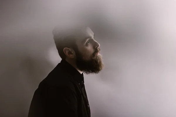 Sepia-Fotoporträt eines stilvollen Mannes im Profil mit Bart im schwarzen Hemd im Nebel — Stockfoto