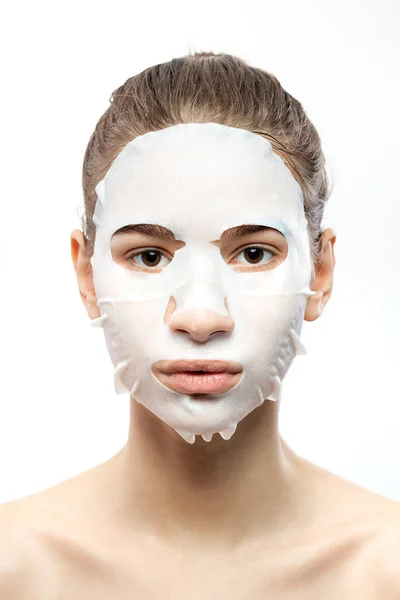 Retrato de uma menina com uma máscara branca hidratante no fundo branco — Fotografia de Stock