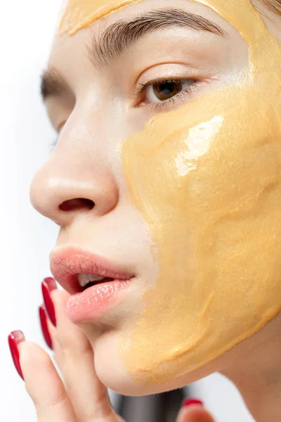 Het gezicht van een jong meisje met gele cosmetische masker op het — Stockfoto