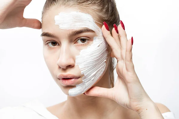 Young woman dressed in white clothes with a white cosmetic mask — Stock Photo, Image