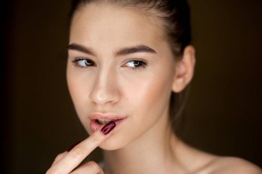 Doğal makyaj parmaklarını yüzünde holding ile genç kahverengi saçlı kız portresi