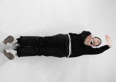 Serbest stil dansçı siyah kot, tişört, şapka ve gri spor ayakkabı giymiş dans Studio beyaz arka plan üzerinde yerdeki yalan