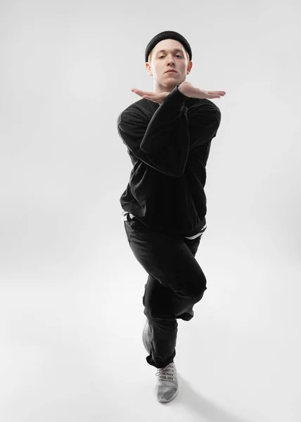 Freestyle dansare klädd i svarta jeans, Sweatshirt, mössa och gråa sneakers dansar i studion på den vita bakgrunden — Stockfoto