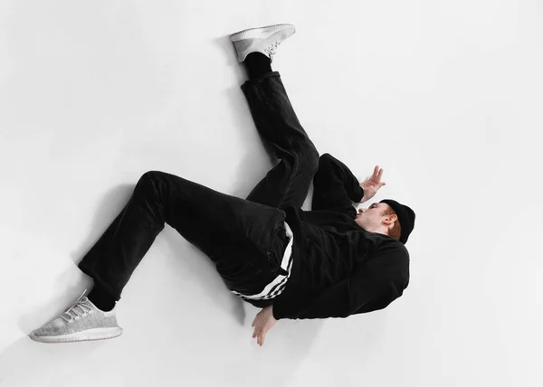 Tańca Freestyle tancerz ubrany w czarne jeansy, Bluza, czapka i szare Adidasy na podłodze w studio na białym tle — Zdjęcie stockowe