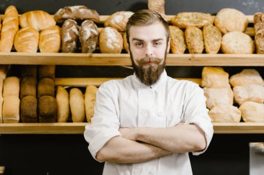 Karizmatik fırıncı fırında taze ekmek ile rafların arka planda duruyor
