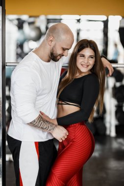 Romantik mutlu atletik çift. Güçlü adam ve ince güzel kız Spor donatımı yanında modern salonunda sarılma