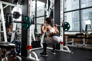 Modern spor salonunda bir halter ile spor ağız kavgası giyinmiş genç atletik kız