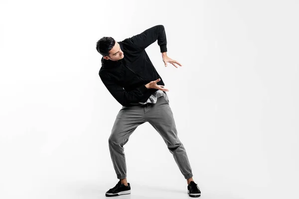 Mörkhåriga ung man klädd i en svart Sweatshirt och grå byxor dansar Street Dance. Han gör stiliserade rörelser med händerna — Stockfoto