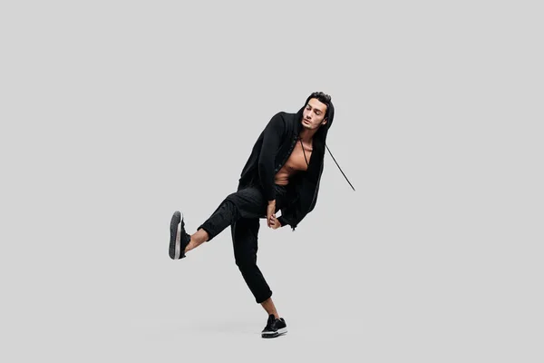 Hezká mladá tanečnice oblečená v černých kalhotách, tričko na nahém trupu zdvihá jednu nohu nahoru, zatímco taneční pouliční tanec — Stock fotografie