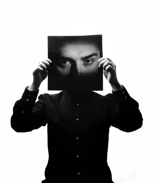 Foto in bianco e nero dell'uomo in camicia nera con in mano una foto con il volto di un uomo al posto del suo volto — Foto Stock