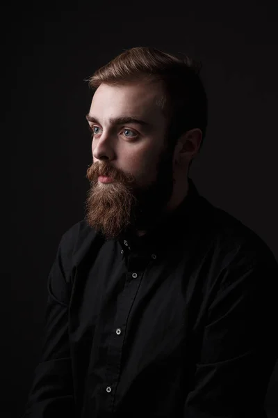 Портрет Сепії стильний чоловік з бородою і стильним зачіскою, одягнений у чорну сорочку на чорному тлі — стокове фото