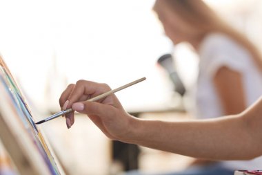 Kızların elinde boya fırçası var. Sanat stüdyosunda şelat resimleri boyama süreci