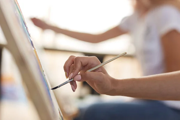 Dívčí ruka má kartáček na barvy. Proces Malování na stojan v uměleckým studiu — Stock fotografie