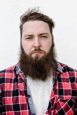 Beyaz arka plan üzerinde kontrol edilmiş bir gömlek giymiş sakallı güçlü vahşi adamın portresi