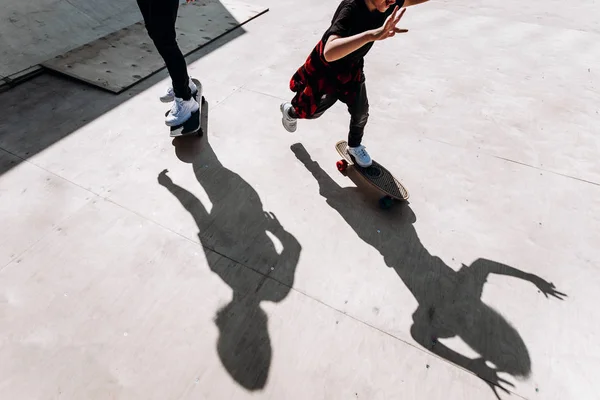De schaduwen van twee mannen staande op de Skateboards op de vloer in een skatepark op de zonnige dag buiten — Stockfoto