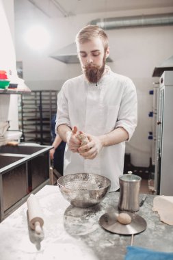 Karizmatik fırıncı sakallı ve bıyıklı fırında masaya hamur yoğurdu