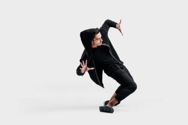 Siyah giysiler giymiş koyu saçlı şık dansçı sokak dansı stilize hareketleri yapar