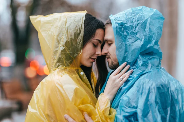 Liebender Kerl und seine Freundin im Regenmantel stehen sich im Regen auf der Straße gegenüber — Stockfoto