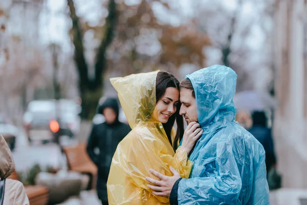 Romantik sevgi dolu çift, adam ve yağmurluk kız arkadaşı yağmurda sokakta yüz yüze durmak — Stok fotoğraf