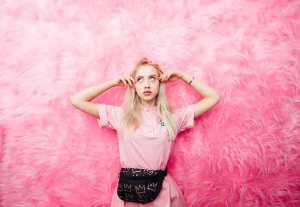 Jovem linda menina loira vestida de vestido rosa de moda posa no fundo da parede de pele rosa na sala de show — Fotografia de Stock