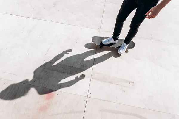 De schaduw van de man staande op het skateboard op de vloer van de glijbaan in een skatepark op de zonnige dag buiten — Stockfoto