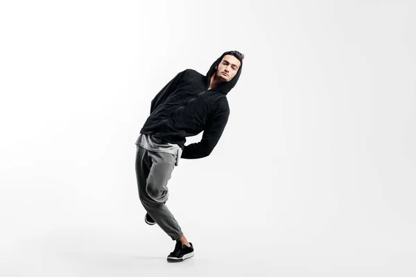 Jeune homme élégant portant un sweat-shirt noir et pantalon gris danse la rue danse sur un fond blanc — Photo