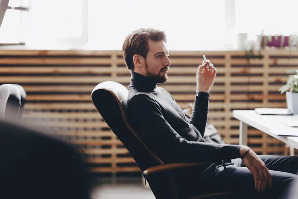 Tipul îmbrăcat în haine casual office este așezat într-un scaun de birou la birou în biroul modern — Fotografie, imagine de stoc