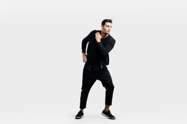 Bir spor siyah elbise giymiş yakışıklı genç sokak dansı dans ediyor.
