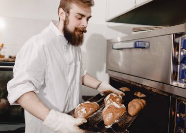 Fırıncı fırından fırıntepsisini çıkarır fırında yeni pişirilen ekmekle fırın tepsisi