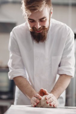 Karizmatik fırıncı sakallı ve bıyıklı fırında masaya hamur yoğurdu
