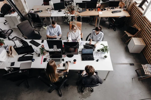 Das Team von Kollegen arbeitet mit Laptop und Dokumenten, die an den Schreibtischen in einem modernen Büro sitzen. Arbeitsprozess im Büro. — Stockfoto