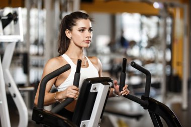 Spor kıyafeti giymiş genç atletik kız modern spor salonunda özel spor ekipmanları ile egzersizleri yapıyor