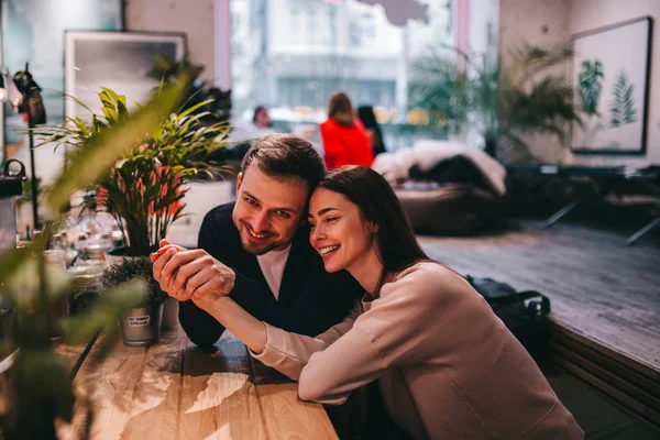 Pria yang bahagia memegang tangan pacarnya duduk di meja di kafe dan menatapnya . — Stok Foto