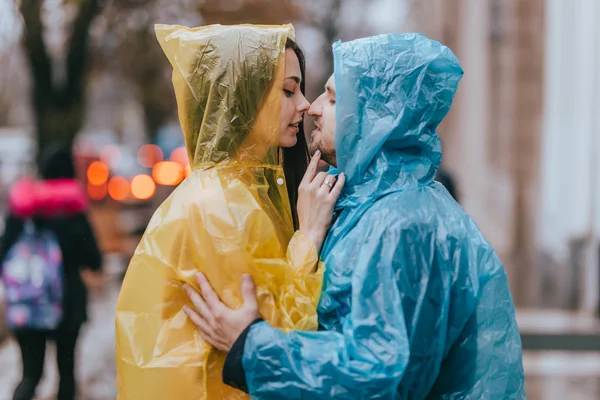 Liebender Kerl und seine Freundin im Regenmantel stehen sich im Regen auf der Straße gegenüber — Stockfoto