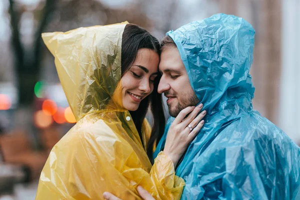 Liebender Kerl und seine Freundin im Regenmantel stehen sich im Regen auf der Straße gegenüber — Stockfoto