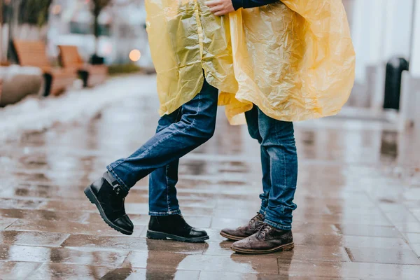 Pernas de cara e menina em jeans e capas de chuva amarelas na rua na chuva — Fotografia de Stock