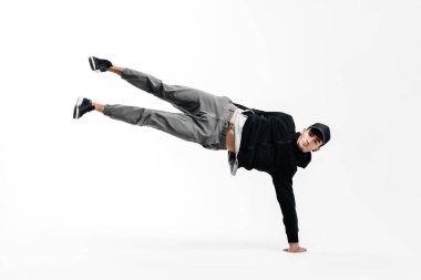 Şık genç dansçı breakdance dans ediyor. Bir kolunun üzerinde duruyor ve iki bacağını kaldırıyor..