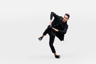 Siyah bir tişört ve siyah pantolon giymiş yakışıklı genç breakdance dans ediyor