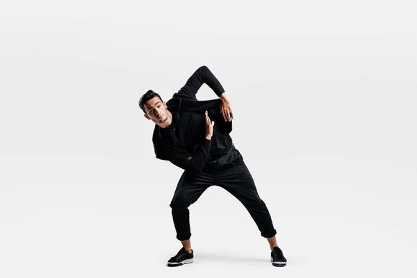 Snygg ung man klädd i en svart Sweatshirt och svarta byxor gör stiliserade rörelser av hip-POH — Stockfoto