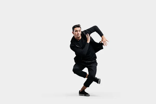 Jovem elegante vestindo uma camisola preta e calças pretas faz movimentos estilizados de hip-poh — Fotografia de Stock